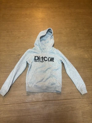 Grå hoodie från Dirt Cult XS - Snygg ljusgrå hoodie från Dirt Cult med svart tryck 'Dirt Cult San Diego' på bröstet. 