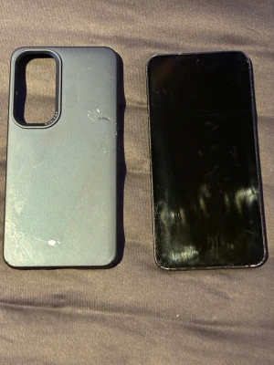 Samsung Galaxy S23 svart med skal - Säljer en Samsung Galaxy S23 i svart med stilren matt finish och tre kameror på baksidan. Telefonen har en modern, slimmad design och kommer med ett mörkblått skyddsskal i plast i nyskick. Den är i mycket bra skick, lite små repor som knappt syns på skärmen, samt lite repor på kanterna. Fungerar precis som den ska,inga problem alls. 1.5 år gammal men endast använd i 1 år. Perfekt för dig som vill ha en kraftfull och snygg mobil. Skriv för fler frågor 👌