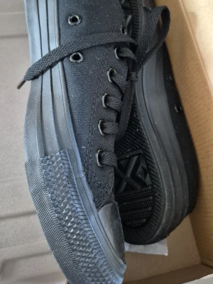 Converse Chuck Taylor All Star svart - Klassiska Converse Chuck Taylor All Star i helsvart utförande. Skorna har canvasöverdel, svarta snören och svart gummisula. Monokrom design med metallöljetter och låg profil som passar till det mesta. Har endast provats.