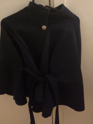 missäy - Svart kappa med knappdetalj, endast använd 2–3 gånger.