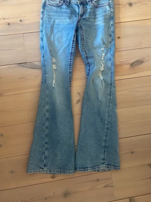 Blå jeans med broderad bakficka -  Säljer ett par jättefina ljusblå jeans från Gina Tricot med hål och slitningar. Jeansen har fina rosa detaljer på fickorna och är i storlek S Med inslängd 78 cm och midjemått rakt över 37 cm. Säljer då det är för korta. Använda max fem gånger.