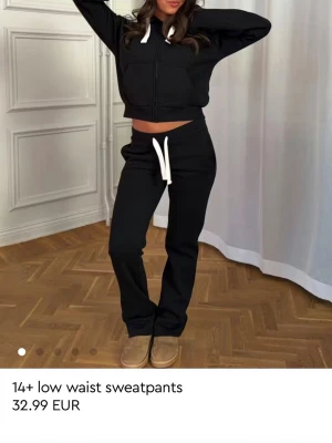 Svarta low waist mjukisbyxor - Snygga svarta mjukisbyxor med låg midja och raka ben. Byxorna har en vit dragsko i midjan för justerbar passform och är tillverkade i ett mjukt sweatshirtmaterial. Perfekta för en chill och avslappnad stil. Säljer pga de är för småa till mig.