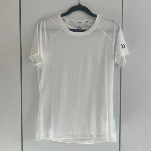 Vit tränings t-shirt - Säljer en vit tränings-tshirt från lager 157 med korta ärmar och rund hals. Tillverkad i ett lätt och snabbtorkande funktionsmaterial, perfekt för träning eller sport. Knappt använd.