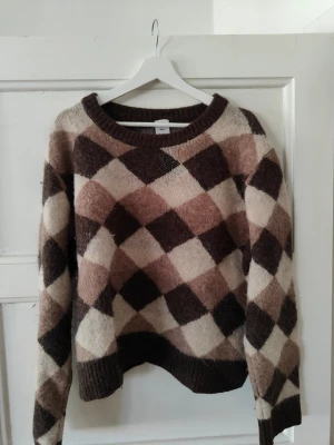 Brun och beige argyle stickad tröja - Won hundred Bently Harlekin (knappt använd). Stickad med argylemönster i bruna, beige och ljusbruna toner. Tröjan har rund halsringning, långa ärmar och ribbade muddar vid ärmslut och nederkant. Materialet är galet mjukt och fluffigt, perfekt för kyligare dagar. Org pris 4000