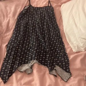 Mörkblått nattlinne med blommönster - Sött nattlinne i mörkblått med små vita blommor och tunna axelband. Nattlinnet har en lös passform och spetsdetaljer längst ner. Perfekt för mysiga kvällar hemma.