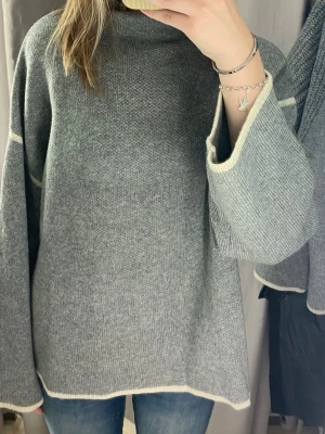 Stickad tröja Zara - Mysig grå stickad tröja med oversized passform och vida ärmar. Tröjan har ljusa kontrastsömmar vid ärmslut och nederkant samt en lite högre hals!✨