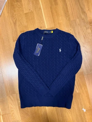 🔥 Ralph Lauren mörkblå stickad tröja – Tjock cable knit / Old Money / Strl M - ✨ Skick: 9/10 (mycket fint skick, inga hål eller fläckar) ✨ Passform: Normal/regular fit ✨ Färg: Mörkblå ✨ Material: Tjock stickad – varm och bekväm  Sitter snyggt både oversized och mer fitted beroende på hur man vill styla den. Funkar perfekt till jeans, kostymbyxor eller över skjorta.  Säljs då den inte används längre. Pris kan diskuteras vid snabb affär 💬 
