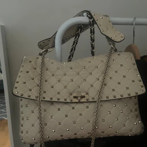 Beige/vit handväska med nitar Valentino - valentino väska !! äkthetsbevis finns, defekter på baksidan men inget som märks när den används! säljer för bra pris 💕💕skulle säga at den är mer åt det vita hållet men lite beige också !