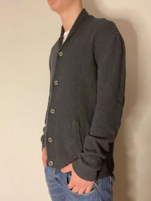 Snygg mörkgrå cardigan - Säljer en mörkgrå cardigan från Tom tailor. Modellen på bilderna är 178cm och väger cirka 70kg. Hör gärna av er vid funderingar eller frågor!