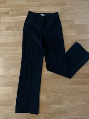 Svarta kostymbyxor från Eight Paris - Snygga svarta kostymbyxor från Eight Paris med raka ben och pressveck. Klassisk midja och hällor för skärp. Perfekta för en clean och stilren look. Materialet känns mjukt och följsamt, vilket gör dem bekväma att bära hela dagen.