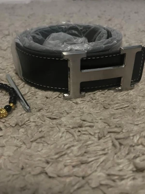 Svart H bälte  - Säljer mitt herrmes bälte 115cm helt nytt. Armband ingår. Hör av er vid frågor och funderingar