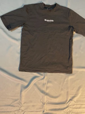 Svart t-shirt från Resteröds - Svart t-shirt från Resteröds med vit logga och text 'Established 1935' på bröstet. Klassisk rund halsringning och korta ärmar. Tillverkad i mjuk bomull för en skön känsla och enkel stil.