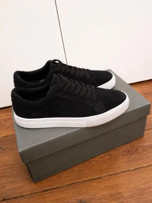 Svarta mocka sneakers från Vagabond - Stilrena svarta sneakers från Vagabond med ovandel i mocka och klassisk vit sula. Skorna har svarta skosnören och låg profil som passar till många olika outfits. Perfekta för dig som gillar en enkel men snygg look.