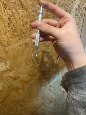 Nagelverktyg och refillkuddar - Säljer ett metallverktyg för naglar med greppvänligt handtag och tvådelad spets, perfekt för att ta bort nagelband eller rengöra under naglarna. Medföljer en ask med vita fyrkantiga refillkuddar som passar till verktyget. Perfekt för dig som gillar nagelvård hemma.