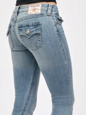 True Religion ljusblå bootcut jeans - Säljer ett par ljusblå bootcut jeans från True Religion med klassiska kontrastsömmar och snygga fickdetaljer med lock och knapp bak. Jeansen har en något utsvängd passform och är tillverkade i mjuk denim med stretch för extra komfort.