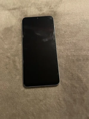 Samsung Galaxy vit Android-telefon - Snygg vit Samsung Galaxy Android-telefon med stor skärm och rundade hörn. Baksidan har fyra kameror och Samsung-logga. Telefonen har en stilren design i plast och glas, perfekt för dig som gillar modern teknik och enkel användning. mobilen är nästan aldrig använt. om du är intresserad så kan vi snacka om priset