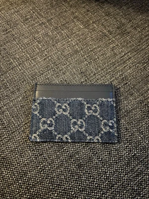 Gucci blå denim korthållare - Snygg korthållare från Gucci i blå denim med klassiskt GG-mönster och svarta läderdetaljer upptill. Perfekt för att hålla koll på dina kort med stil. Den kompakta designen gör den smidig att ha i fickan eller väskan. Nypris 2200