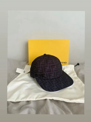 Svart keps med FF-mönster från Fendi - Snygg svart keps från Fendi med det klassiska FF-monogrammönstret över hela kepsen. Kepsen har böjd skärm och justerbar rem bak. Tillverkad i ett slitstarkt tyg som känns lyxigt och trendigt. Perfekt accessoar för dig som gillar exklusiva detaljer. Box och påse kommer ej med