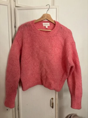 Rosa stickad tröja med rund hals - Mysig rosa stickad tröja med rund halsringning och långa ärmar. Tröjan har en avslappnad passform och ribbstickade muddar vid ärmslut och nederkant. Perfekt för lager på lager och ger en färgklick till din outfit. Pris kan diskuteras💖