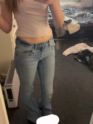 Ljusblå bootcut jeans med låg midja - Säljer ett par ljusblå bootcut jeans med låg midja och klassiska fickor både fram och bak. Jeansen har en avslappnad passform och är perfekta för en chill och trendig look. Passar dig som gillar 00-talsstil.