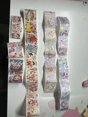 Söta klistermärken med djurmotiv - Flera ark med färgglada klistermärken i olika former och storlekar. Motiven är gulliga djur, tecknade figurer, stjärnor och hjärtan i pastellfärger som rosa, lila, gul och blå. Perfekt för att dekorera anteckningsböcker, brev eller pyssel.