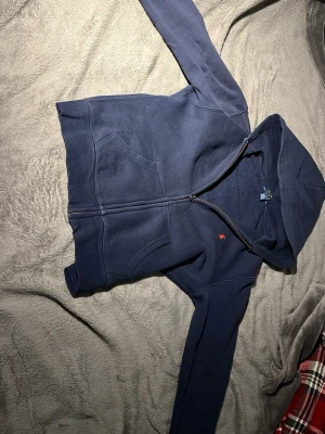 Mörkblå hoodie med dragkedja - Mörkblå hoodie från POLO RALPH LAUREN då jag köpte den på kids brand store för cirka 1200kr jag säljer den för 650kr ingen fläck eller hål som helt ny använt några gånger passar 10-12 år gammal skriv vid intressen 