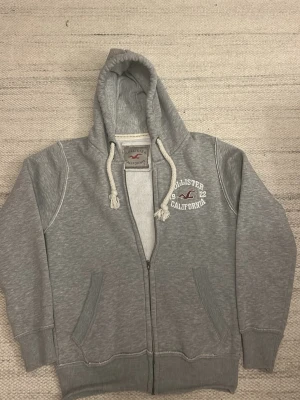 Hollister tröja - Säljer denna zip up från hollister i stolek s men sitter något mindre. Den är i gott skick förutom armhålan som håller på att släppa lite. Har du frågor eller funderingar hör gärna av dig.