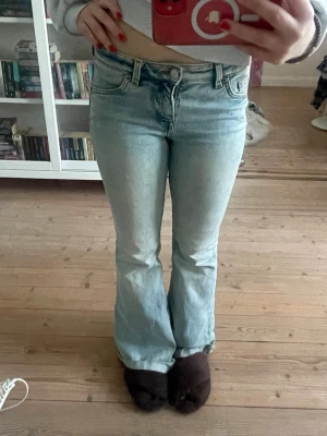 Ljusblå bootcut jeans med låg midja - Säljer ett par ljusblå bootcut jeans med låg midja. Jeansen har en lätt tvättad look och vida ben nedtill. Ner till benen har jag klippt av så dom skulle passa min längd därav lite slitet ner till. 