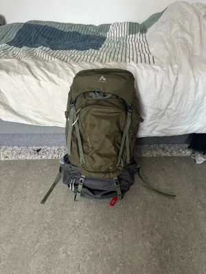 Grön ryggsäck från McKinley - Stor och robust grön ryggsäck från McKinley med flera fack, justerbara axelremmar och vadderat höftbälte. Perfekt för längre äventyr eller resor. Tillverkad i slitstarkt syntetmaterial och har smarta spännen och detaljer för extra komfort.