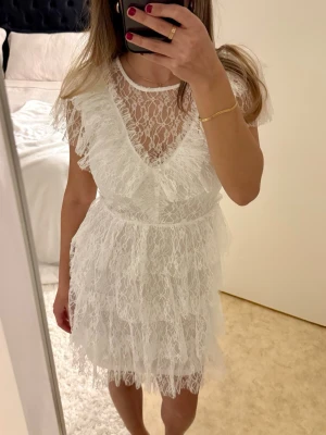 Studentklänning - Säljer min fina studentklänning från Bubbleroom i storlek XS🤍 Vit klänning i spets med volanger, kort modell. Använd endast 1 gång, som ny. Nypris ca 900kr.