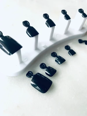 Prisförslag - 10 Svarta glansiga press-on naglar återanvändbara - Snygga press-on naglar i en klassisk svart färg med glansig finish. Naglarna har en rak, något fyrkantig form och är perfekta för dig som vill ha en stilren look. Materialet är plast och de är enkla att applicera. Kan återanvändas flera gånger om. 