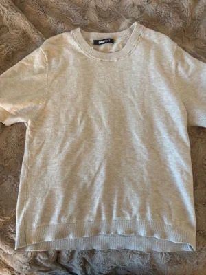 Beige kortärmad topp Gina Tricot - En enkel och stilren beige topp från Gina Tricot. Modellen har korta ärmar, rund halsringning och är gjord i ett mjukt material som känns skönt mot huden. Perfekt att matcha med jeans eller kjol för en clean look.