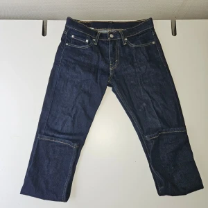 Levi's mörkblå raka jeans - Säljer ett par klassiska mörkblå jeans från Levi's med raka ben och kontrastsömmar. Jeansen har fem fickor, knappgylf och tydlig läderpatch bak i midjan. Tillverkade i slitstark denim, perfekta för en clean och tidlös look.