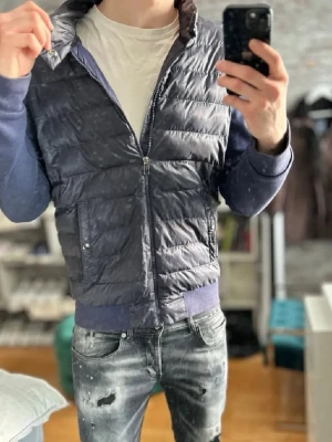 Mörkblå cardigan  från Polo Ralph Lauren - Snygg mörkblå cardigan från Polo Ralph Lauren med quiltad design och dragkedja framtill. Västen har ribbade muddar i nederkant och vid kragen samt två fickor med knappstängning. Perfekt för lager på lager och streetwear-vibe.