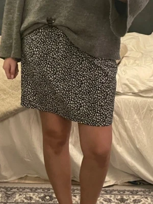 Svartvit kortkjol med prickigt mönster och fickor - Säljer en svartvit kortkjol med prickigt mönster. Kjolen har en rak passform och är tillverkad i ett mjukt tyg som känns bekvämt mot huden. Perfekt att matcha med en stickad tröja eller t-shirt för en avslappnad look.