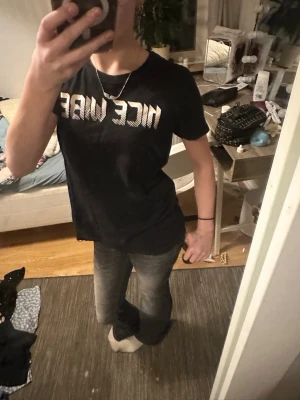 Svart t-shirt med NICE VIBE-tryck - Snygg svart t-shirt med coolt vitt 'NICE VIBE'-tryck framtill. Klassisk passform och rund halsringning, perfekt till jeans eller shorts. Tillverkad i mjuk bomull för skön känsla hela dagen.