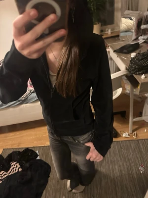 Svart velour hoodie med dragkedja - Mjuk och skön svart hoodie i velour från cubus. Hoodien har dragkedja framtill, fickor och en klassisk huva. Perfekt för en avslappnad och trendig look. Passar till jeans eller mjukisbyxor.