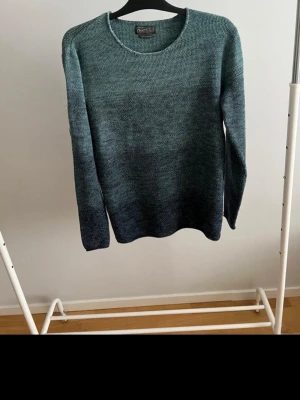 Grönmelerad stickad tröja - Snygg stickad tröja från Jack&Jones i grönmelerad färg med rund halsringning och långa ärmar. Tröjan har en mjuk och skön känsla, perfekt för kyligare dagar. Enkel och stilren design som passar till mycket.