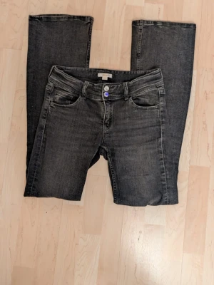 Mörkgrå bootcut jeans - Säljer ett par mörkgrå bootcut jeans från Gina Tricot. Jeansen har en utsvängd passform nedtill och är tillverkade i denim. Perfekta för dig som gillar retrostil och vill ha ett par bekväma jeans. Jeansen är lappade baktill men dwt syns knappt utifrån, kolla bild 4 och 5. 💕💕😊