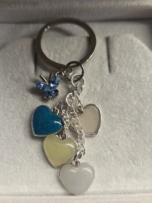 Nyckelring med hjärtan & fjäril – LYSER I MÖRKER! - Säljer en unik, handgjord nyckelring med en charmig och personlig touch. Den består av en glittrig blå fjäril och fyra hjärtformade hängen i matchande färger. ​Det bästa: Hjärtana är självlysande och glöder vackert i mörkret efter att ha fått lite vanligt dagsljus på sig. (se bilderna för den häftiga effekten!).