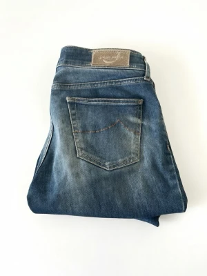 Jacob Cohen Jeans - Snygga blå jeans med klassisk femficksdesign och slitningar för en avslappnad look. Jeansen har en tydlig bakficka och patch med logga bak i midjan. Perfekta till en casual outfit och passar till det mesta.