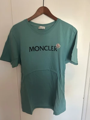 Grön Moncler t-shirt med logga - Snygg grön t-shirt från Moncler med klassisk svart logotyp på bröstet och oanvänd passar både för L/XL