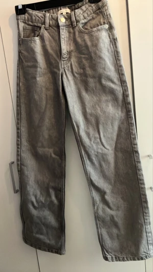 Grå raka jeans från Gina Tricot - Snygga grå jeans från Gina Tricot med rak passform och klassisk femficksdesign. Jeansen har hög midja och är tillverkade i ett mjukt denimtyg. Perfekta för en avslappnad och trendig look.