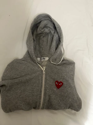 CDG zip - CDG zip. Otroligt populär just nu. Vanligt märke på framsidan och välldig snygg design på baksidan. Storleken står att det är medium men passar mest storlek S, kanske till och med XS.