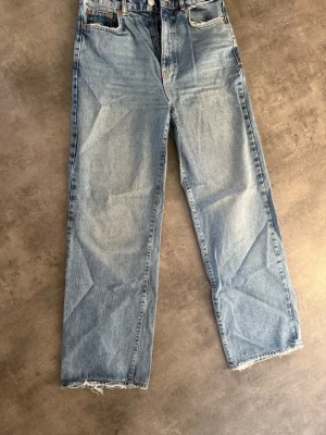 Ljusblå raka jeans från Gina Tricot - Ljusblå jeans med rak passform från Gina Tricot. Klassisk femficksmodell med hög midja och råa, fransiga benslut. Perfekta för en avslappnad och trendig look. Tillverkade i denim av bomull.