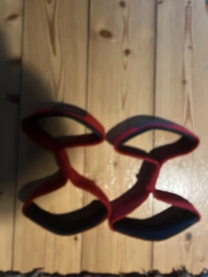 Röda träningsband från C.P. Sports - Säljer ett par röda träningsspelade  från C.P. Sports, perfekta för styrketräning och gym. De är tillverkade i slitstarkt material med svarta detaljer och har en ergonomisk design som ger bra grepp vid lyft.