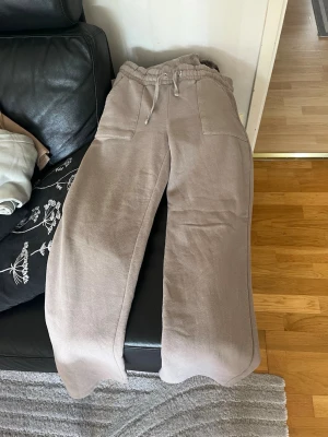 Beige mjukisbyxor med raka ben - Säljer ett par beige mjukisbyxor med raka ben och resår i midjan samt dragsko. Byxorna har stora fickor fram och två bakfickor. Perfekta för chill dagar och riktigt sköna tack vare det mjuka materialet.