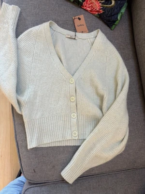 Turkos ribbad kofta från Gina tricot premium - Superfin turkos ribbstickad kofta från ginatrickot premium. Tror mohair, kashmir av något slag. med v-ringning och fyra knappar framtill. Kortare modell med långa ärmar och mjukt material som känns skönt mot huden. Perfekt att slänga på sig över en topp.