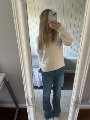 Blå bootcut jeans i denim - Säljer ett par blå bootcut jeans med normal midja och raka ben. Jeansen är gjorda i klassisk denim och har en avslappnad passform som ger en snygg siluett. Perfekta för dig som gillar en tidlös och trendig look.
