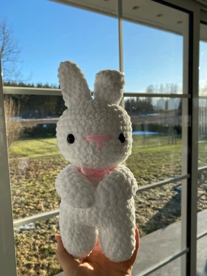 Vit virkad kanin med rosa fluga - Söt handgjord kanin i mjukt vitt garn med en rosa liten fluga. Perfekt som dekoration eller gosedjur.